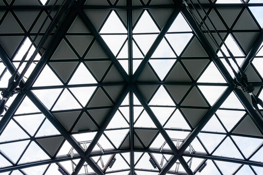 Geometric architectural background of modern steel and glass roof structure with triangular patterns seen from below