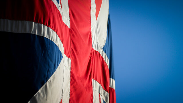 British Union Jack Flag. Close up of the national fabric symbol waving against a clear blue sky background with copy space.