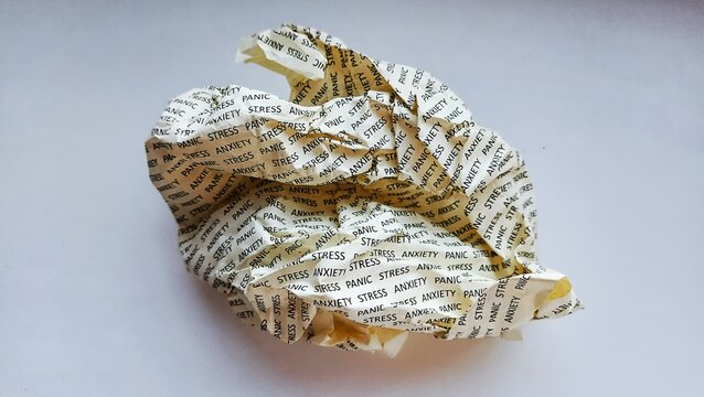 Ball of crumpled paper with printed text stress, anxiety and panic on white background. Mental health and burnout concept.