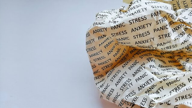 Crumpled paper sheet with text stress, anxiety and panic attack on white background. Mental health and burnout concept.