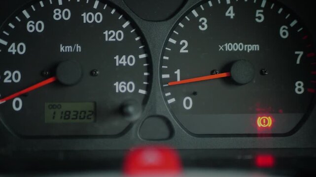 Close-up of car dashboard with red brake warning light illuminated. Vehicle safety and maintenance concept.