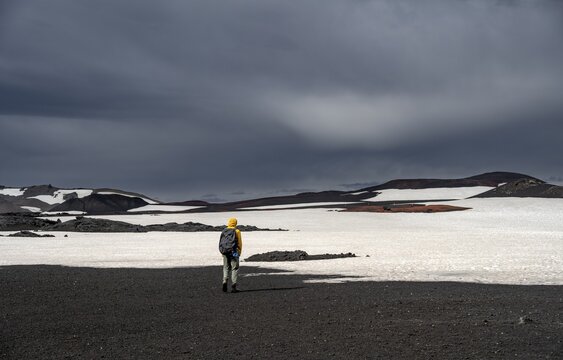 Hikers in snow-covered volcanic landscape with volcanic sand and petrified lava, crater of Askja volcano, Icelandic highlands, Iceland
