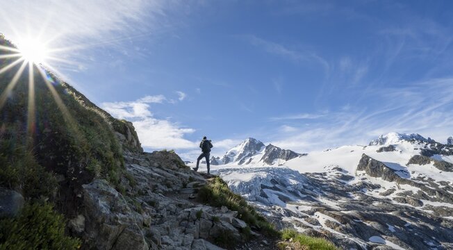 Mountaineer in front of high alpine mountain landscape with sun star, summit of Aiguille de Chardonnet and Glacier du Tour, glacier and mountain peaks, Chamonix, Haute-Savoie, France