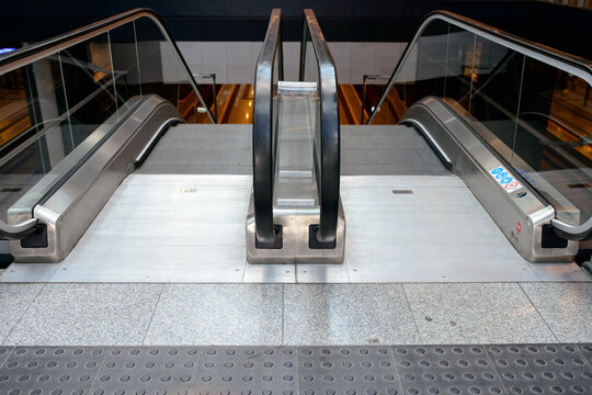 High angle symmetrical view of empty modern escalators leading down inside a public transit station or shopping mall