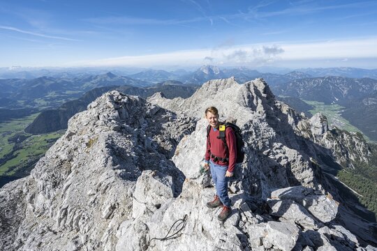 Hiker in rocky terrain, ascent to Mitterhorn, mountain panorama, rocky ridge with peaks &Ouml;stliches Rothorn and Gro&szlig;es Rothorn in the background, Nuaracher H&ouml;henweg, Loferer Steinberge, Tyrol, Austria