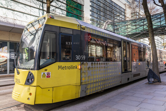 Yellow and grey Metrolink tram on Corporation Street in Greater Manchester, England.