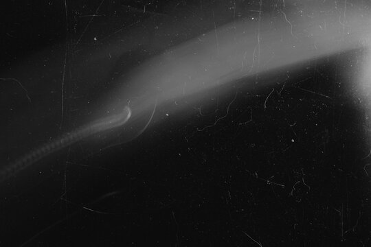 Cinematic black and white film damage overlay with diagonal light flare and dust