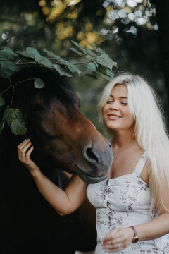 A blonde woman walks with horses in the forest