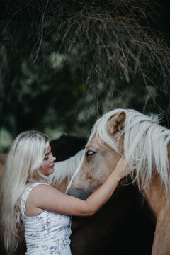 A woman with white hair next to a horse with a white mane. Concept of hair strength and health.