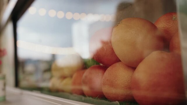 Oranges behind glass with people reflections