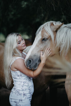Blonde woman with horses in the garden in summer