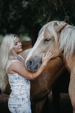 A woman with white hair next to a horse with a white mane. Concept of hair strength and health.