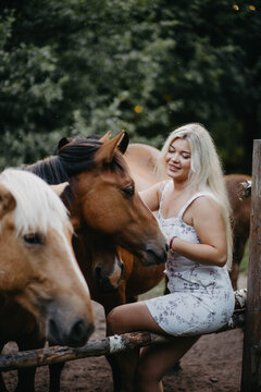 Blonde woman with horses in the garden in summer