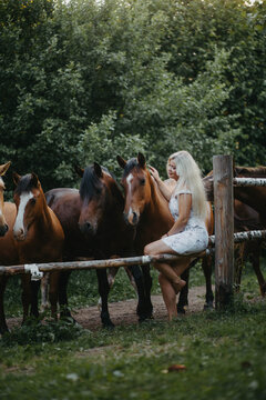 Blonde woman with horses in the garden in summer