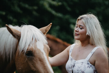 Fototapeta premium Blonde woman with horses in the garden in summer