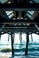 Fototapeta premium Underneath view of a wooden pier over ocean water