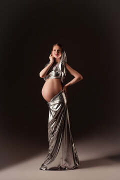 A pregnant slim girl poses in different looks in a photo studio