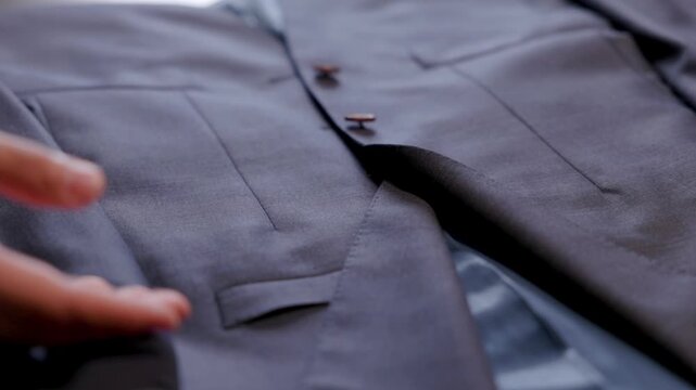 a salesperson's hands run through a suit jacket showing off the quality of fabric