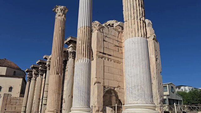 Athens, Greece - 22 June 2026. Low angle view of restored fluted columns and the Roman facade inside Hadrian's Library beneath a cloudless sky.