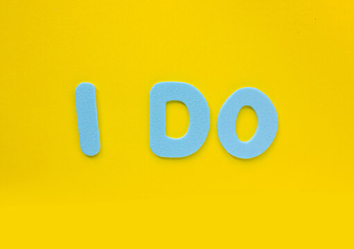 Blue Foam Letters Forming the Phrase "I DO" on Bright Yellow Background. Minimal Creative Typography Concept with Copy Space for Love, Wedding, Commitment and Positive Messages