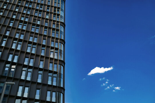 A modern black metal facade of an apartment building with large windows set against a bright blue sky in Moscow's ZIL district. Conceptual architecture.