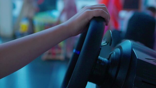 focused adult driving simulation setup in indoor gaming environment with steering wheel and pedals over the shoulder view in black and red plastic and metal materials.