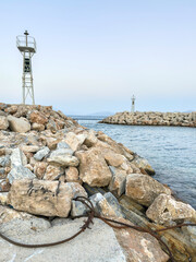 Fototapeta premium Lighthouses on rocky breakwaters at Agios Kirikos harbor, Ikaria island, Greece