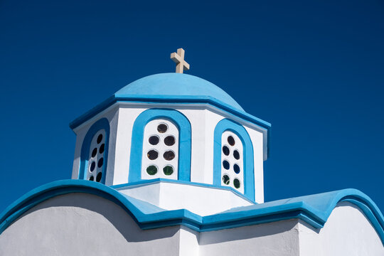 White Greek Orthodox chapel with blue dome under clear sky in Ikaria island, Greece