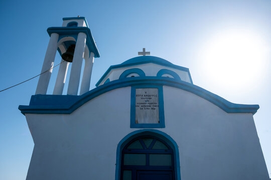 White and blue Greek Orthodox chapel by the sea in Ikaria island under blue summer sky, Greece