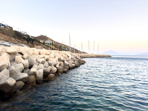 Concrete breakwater and sailboat masts at dusk in Agios Kirikos on Ikaria island Greece