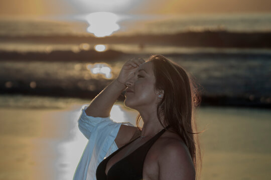 Woman enjoying golden hour sunset on beach feeling relaxed