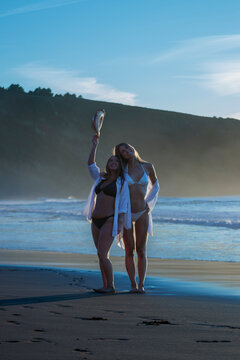 Friends enjoying summer vacation on beach at sunset