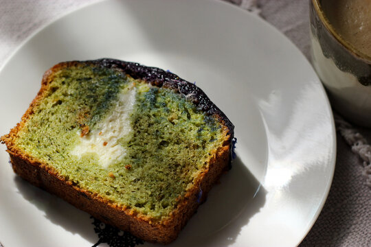 Matcha cupcake on a plate. Matcha loaf cake with a creamy cheese filling. Moist texture and vibrant green tea crumb for dessert and baking concepts.