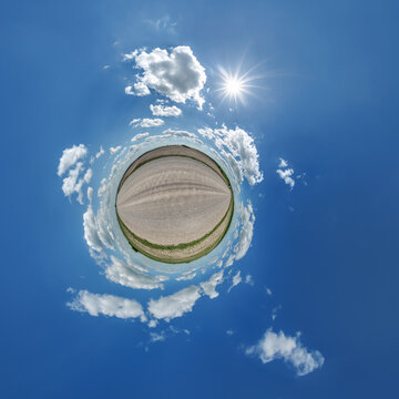 simple little tiny planet without buildings in blue sky with sun and beautiful clouds. Transformation of spherical panorama 360 degrees. Spherical abstract aerial view. Curvature of space.
