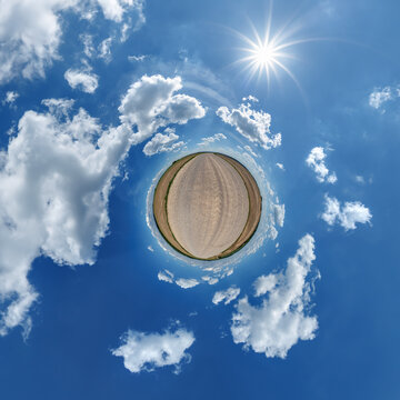 simple little tiny planet without buildings in blue sky with sun and beautiful clouds. Transformation of spherical panorama 360 degrees. Spherical abstract aerial view. Curvature of space.