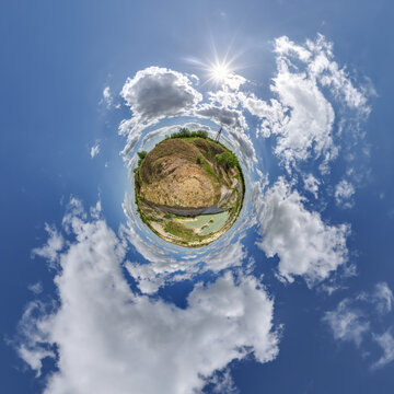 simple little tiny planet without buildings in blue sky with sun and beautiful clouds. Transformation of spherical panorama 360 degrees. Spherical abstract aerial view. Curvature of space.