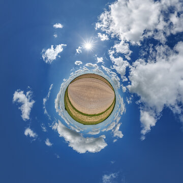 simple little tiny planet without buildings in blue sky with sun and beautiful clouds. Transformation of spherical panorama 360 degrees. Spherical abstract aerial view. Curvature of space.