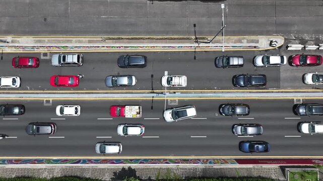 Aerial top-down close-up of heavy traffic on the Viaducto in Mexico City with the drone ascending vertically over the multi-lane avenue and moving cars