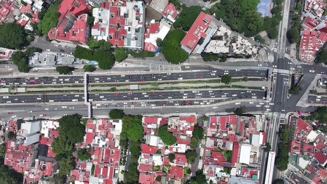 Aerial top-down view of heavy traffic flowing along the Viaducto highway in Mexico City, drone tracking sideways over the multi-lane road and dense neighborhoods