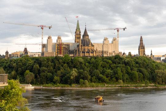 Parliament Hill view from river with small boat cruising Ottawa River in Canada.
