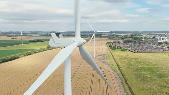 Wind Turbines Turning Over Expansive Fields Beside a Large Power Station Complex