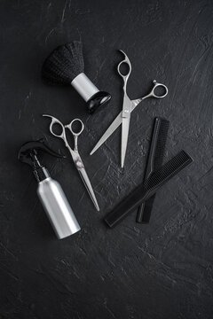 Professional hairdresser tools on a black textured concrete background.