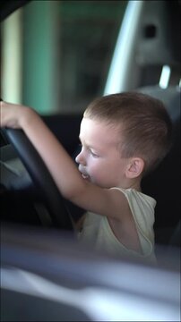 Joyful little boy turns the steering wheel with a big smile, pretending to drive the car. Heartwarming childhood moment inside the vehicle interior.