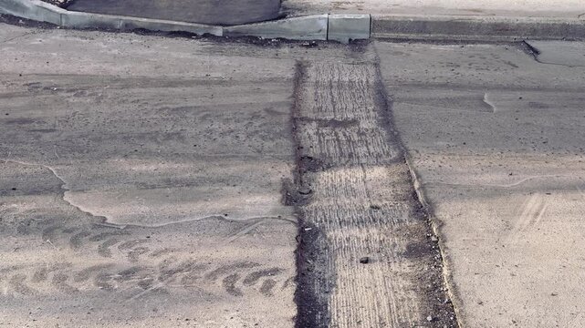 Spring highway pothole preparation empty asphalt, milled edge and loose gravel along curb under soft spring sunlight close-up
