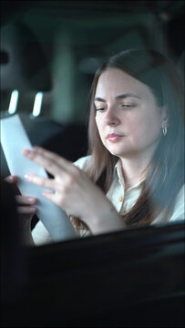 Young woman in a car carefully reviews a long paper receipt from her expensive shopping purchases, checking expenses and budget inside the vehicle.