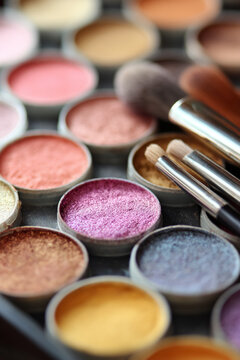 Makeup artist eyeshadow palette with colorful shimmery pigments and cosmetic brushes, creating beauty looks