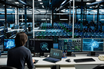 Obraz premium IT specialist working with computer in high tech computing hub with equipment supporting deep learning scientific simulations with computer scientist in server facility doing checkup on rackmounts.