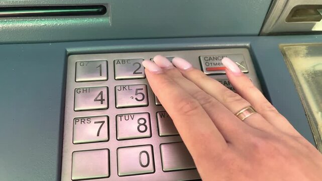 Woman entering pin on atm keypad for banking transaction