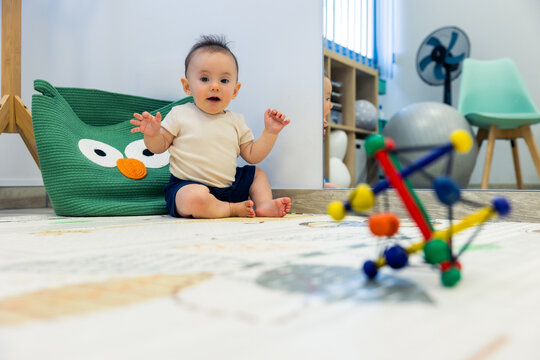 Baby exploring playroom with developmental toy and soft rug