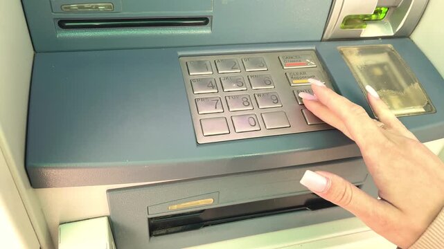 Woman's hand with long nails pressing buttons on an atm keypad during a financial operation
